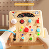 A child's hands interact with a Montessori busy machine circuit board featuring switches, lights, and a switching current sim