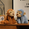 A pair of soft plush monkey toys, one brown and one blue, sitting on a wooden surface.