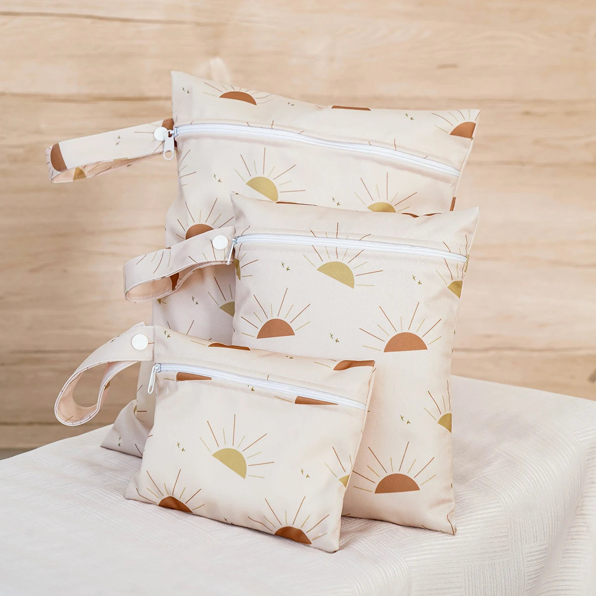 A set of three beige waterproof wet and dry bags featuring a sun design, displayed on a light fabric.