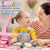A woman is demonstrating a pink button maker machine to a young girl, showing how to make buttons.