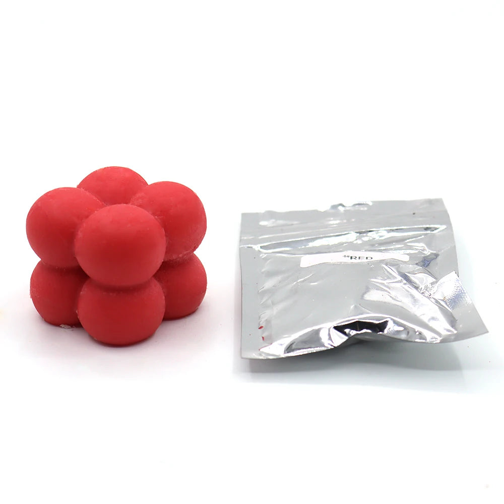 A small plastic bag containing red candle dye chips for wax.