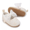 A pair of light beige lace-trimmed baby girl moccasin shoes with a decorative bow.