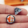 A miniature Japanese sushi set with orange-colored food items and a triangular card resting on a hand.