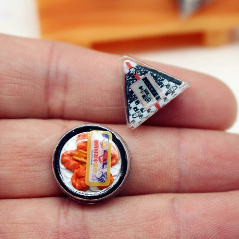 A miniature Japanese sushi set with orange-colored food items and a triangular card resting on a hand.