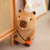 A brown capybara plush toy wearing a white chick on its head and an orange accessory.