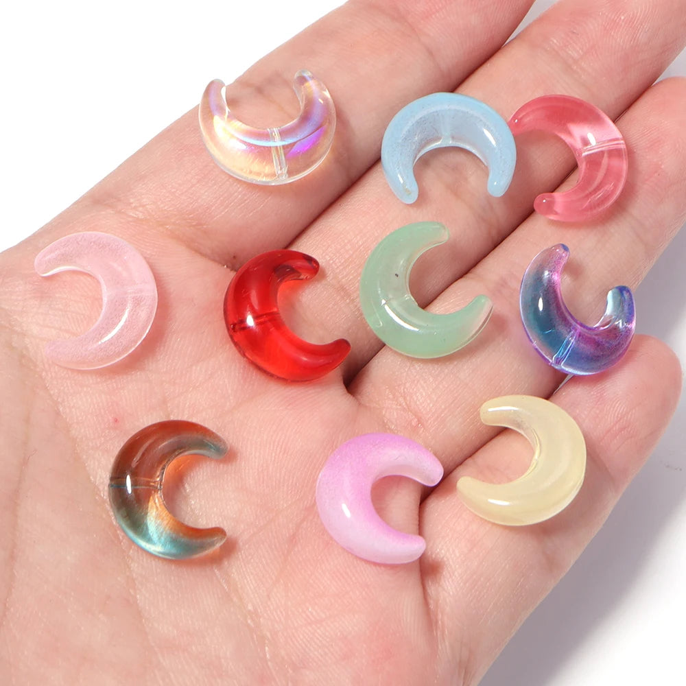 A collection of moon-shaped glass beads in various colors including pink, blue, green, and red, displayed on a hand.