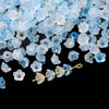 A pile of light blue and clear gradient bellflower acrylic beads for jewelry making