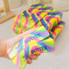 A hand holds a stack of colorful butter stick squishy toys with yellow, pink, and blue gradients.