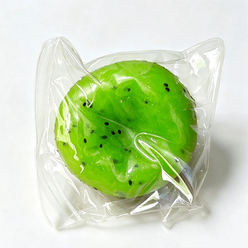 A bright green watermelon kiwi squishy stress ball fidget toy is sealed in a clear plastic bag.