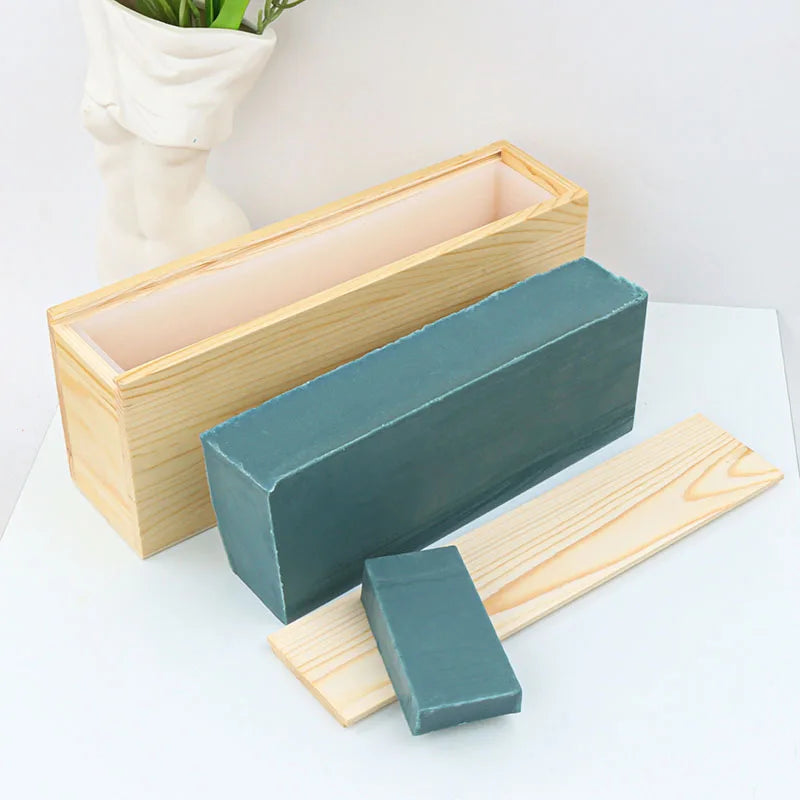A silicone rectangle soap mold is shown with a wooden box and lid on a white surface.