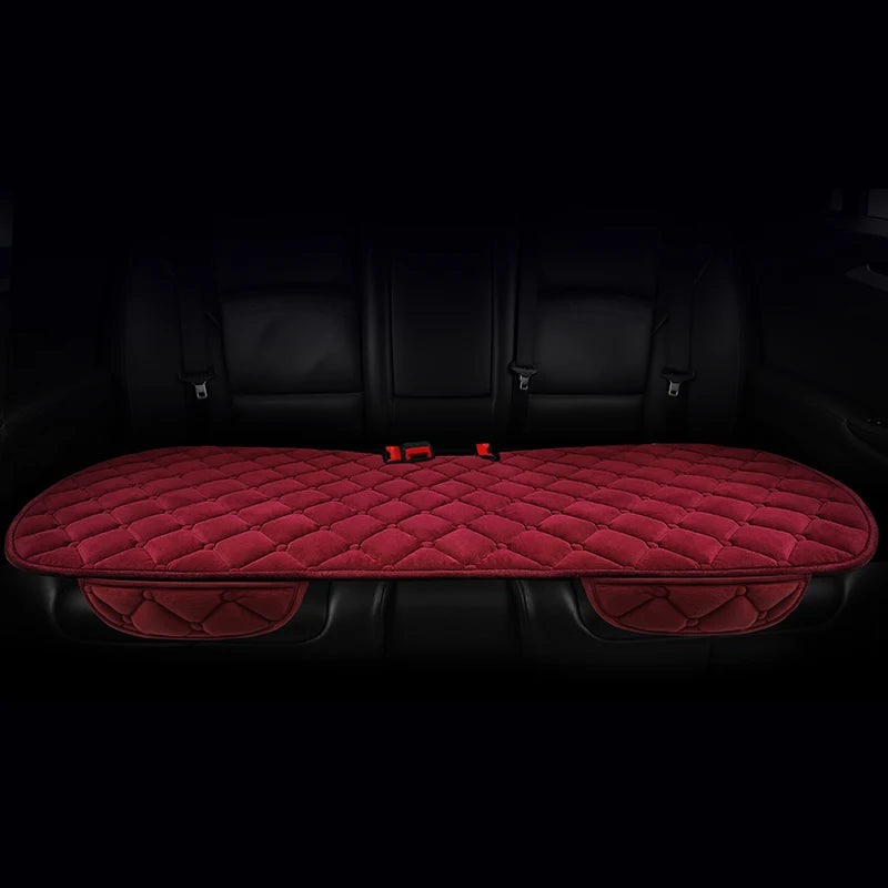 A set of three red quilted car seat cushions with black trim and fasteners shown in a dark interior.