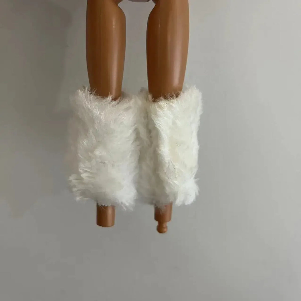 A brown doll figure with white fluffy sleeves hanging against a light gray background.