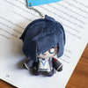 A dark gray anime character plushie pendant charm is displayed on a piece of paper.