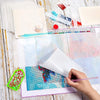 A hand is placing glitter onto a sheet of double-sided non-stick release paper for diamond painting.