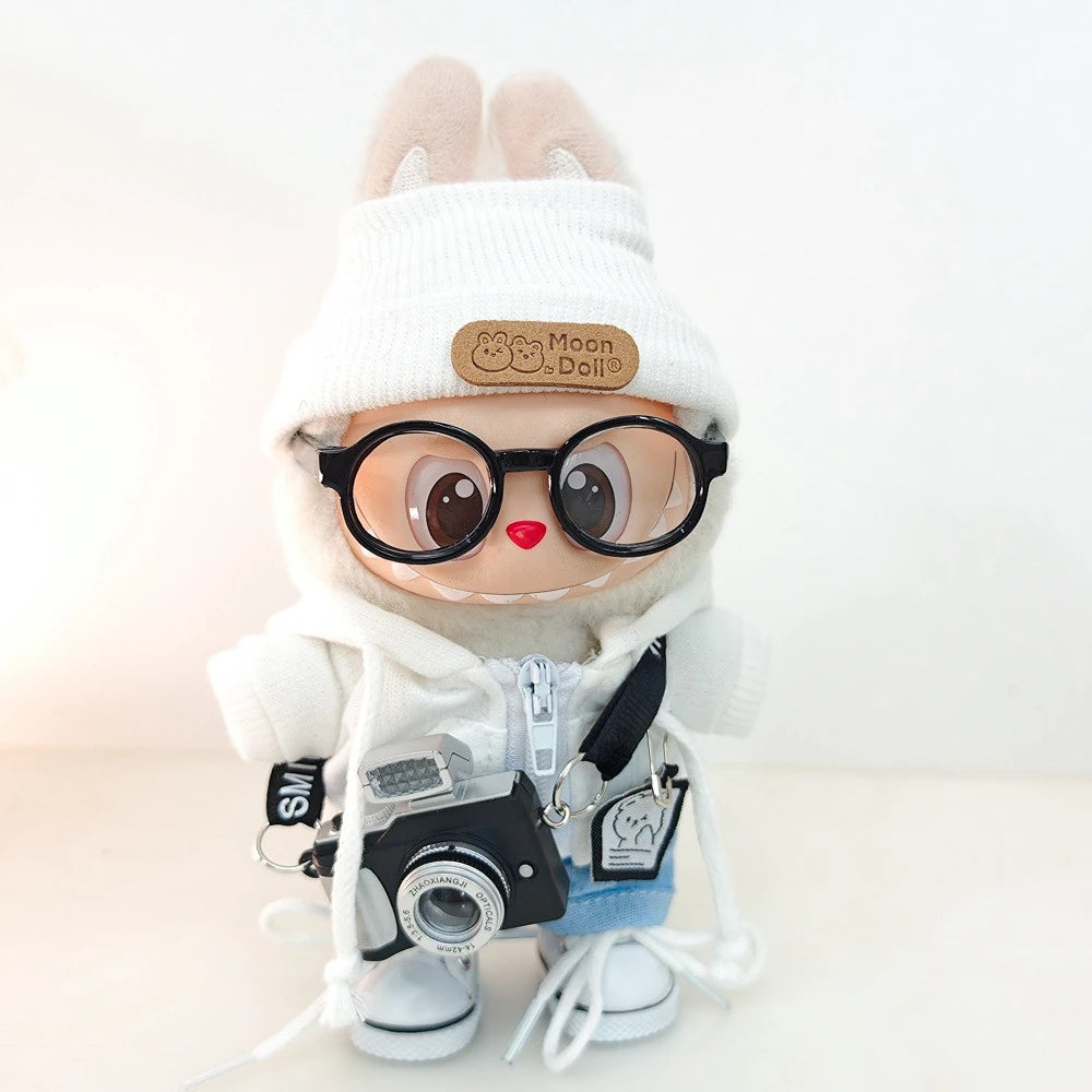 A Labubu doll wearing a white hoodie and headphones with a black frame and a small camera attached.
