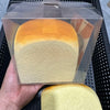A clear plastic package containing a squishy toy shaped like a loaf of bread with an orange and yellow gradient color.