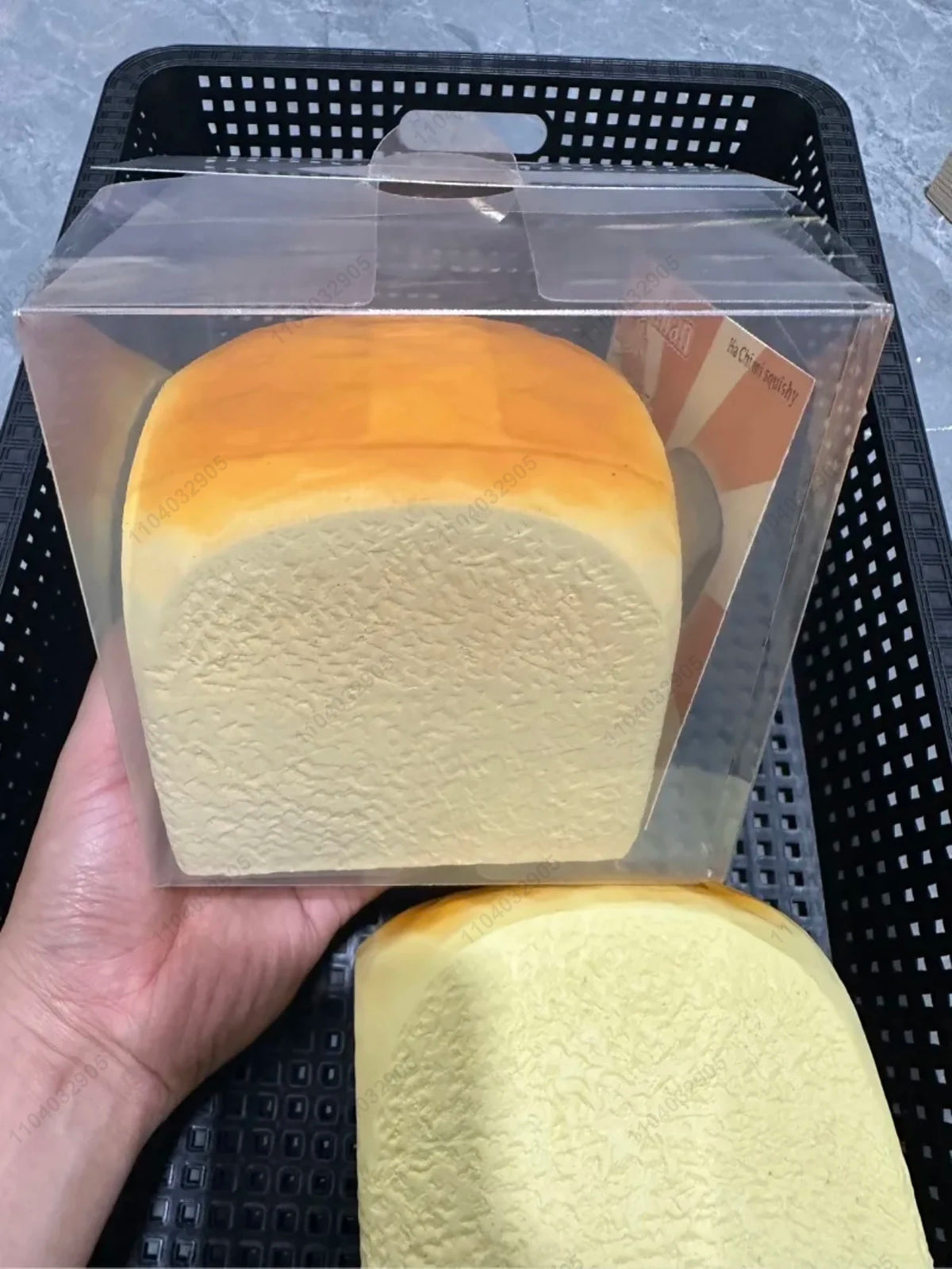A clear plastic package containing a squishy toy shaped like a loaf of bread with an orange and yellow gradient color.