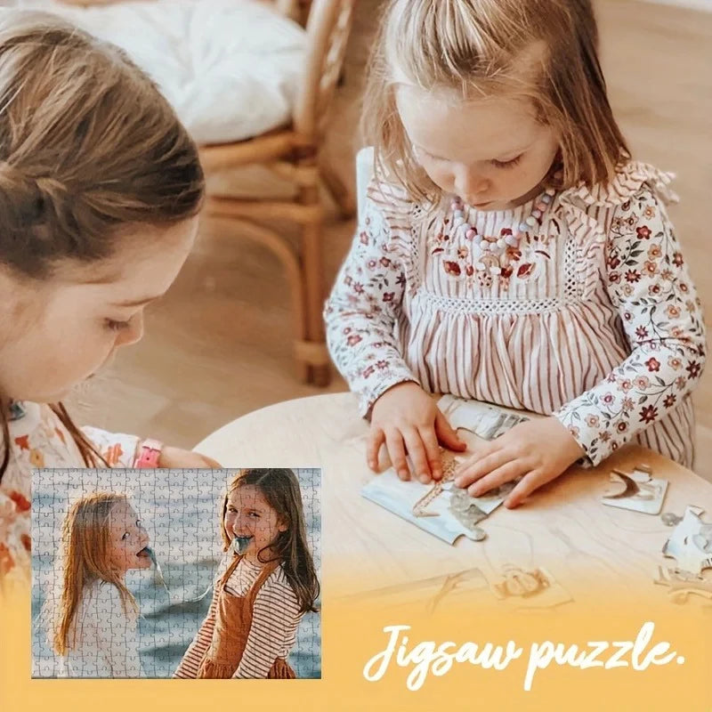 A young girl is assembling a photo jigsaw puzzle on a wooden table with an adult nearby.