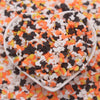 A small white bowl filled with colorful cartoon polymer clay slices in orange, yellow, and black.
