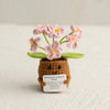 Handmade crochet plant with pink flowers growing from a brown pot