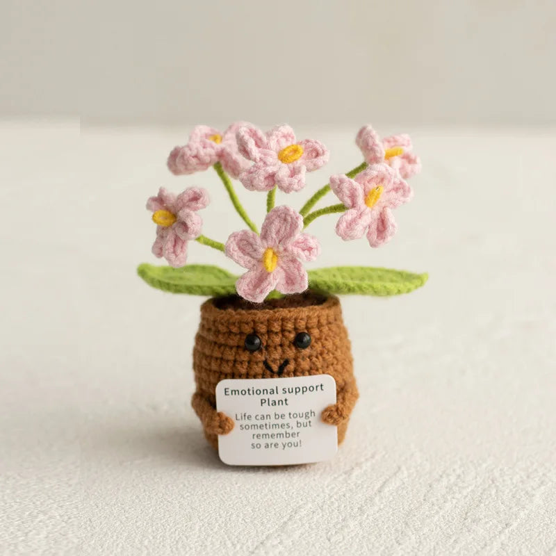 Handmade crochet plant with pink flowers growing from a brown pot