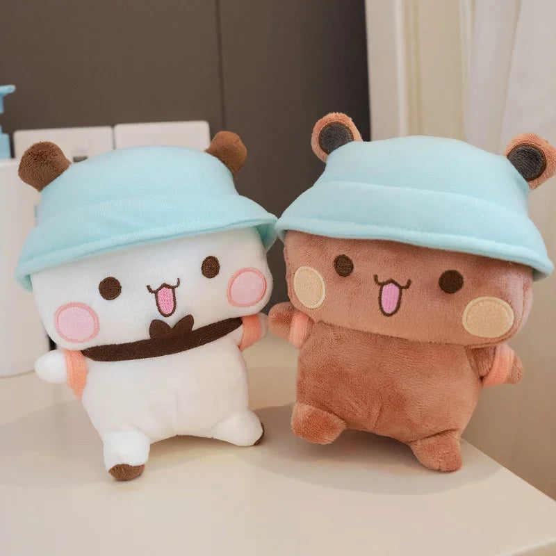 A pair of cute panda bear plush toys with light blue hats sitting on a white surface.