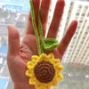 Hand holding a handmade crochet sunflower charm with green stem and yellow petals