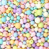 A close-up view of a large pile of colorful matte acrylic beads in various pastel shades.
