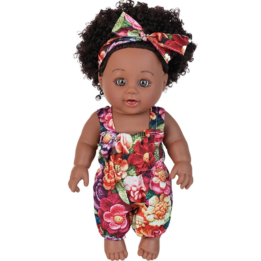 A 12-inch realistic African American baby doll wearing a floral patterned romper and a bow in her hair.