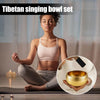 A woman is sitting in a meditative pose holding a golden Tibetan singing bowl set.