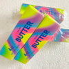 A collection of four rainbow colored butter stick squishies with the word BUTTER printed on them.