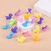 A collection of colorful plastic animal and dinosaur figures in various shades of purple, pink, yellow, and blue arranged on 