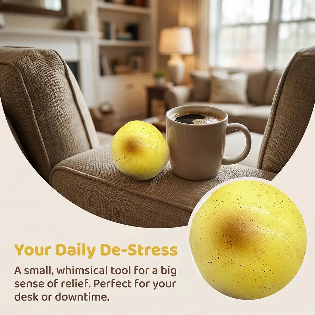 A yellow fluid potato squishy toy resting on a desk next to a cup of coffee.