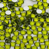 A close-up view of small, round, faceted green glass crystals and white rhinestones for craft projects.