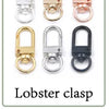 A collection of ten metal lobster clasps in various finishes including silver, gold, and black.