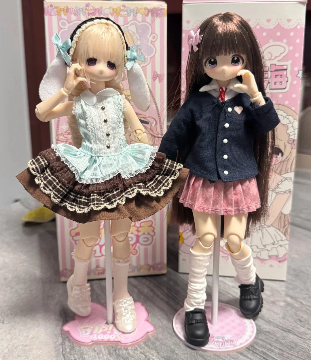 A collectible figure of a girl with long dark hair and a dark blue outfit standing in front of its packaging box.
