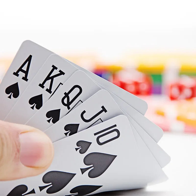 A hand holds a fan of black and white playing cards, showing the Ace, King, Queen, Jack, and Ten cards.