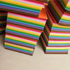 A stack of vibrant felt fabric sheets in a rainbow color spectrum, showing various stripes and colors.
