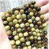A hand holds a string of natural stone beads including amethyst, garnet, and labradorite for DIY jewelry making.