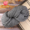 A ball of gray premium alpaca blend yarn is shown on a wooden surface.