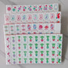 A stack of four layers of pearl pink acrylic American Mahjong tiles featuring various colored and patterned tiles.