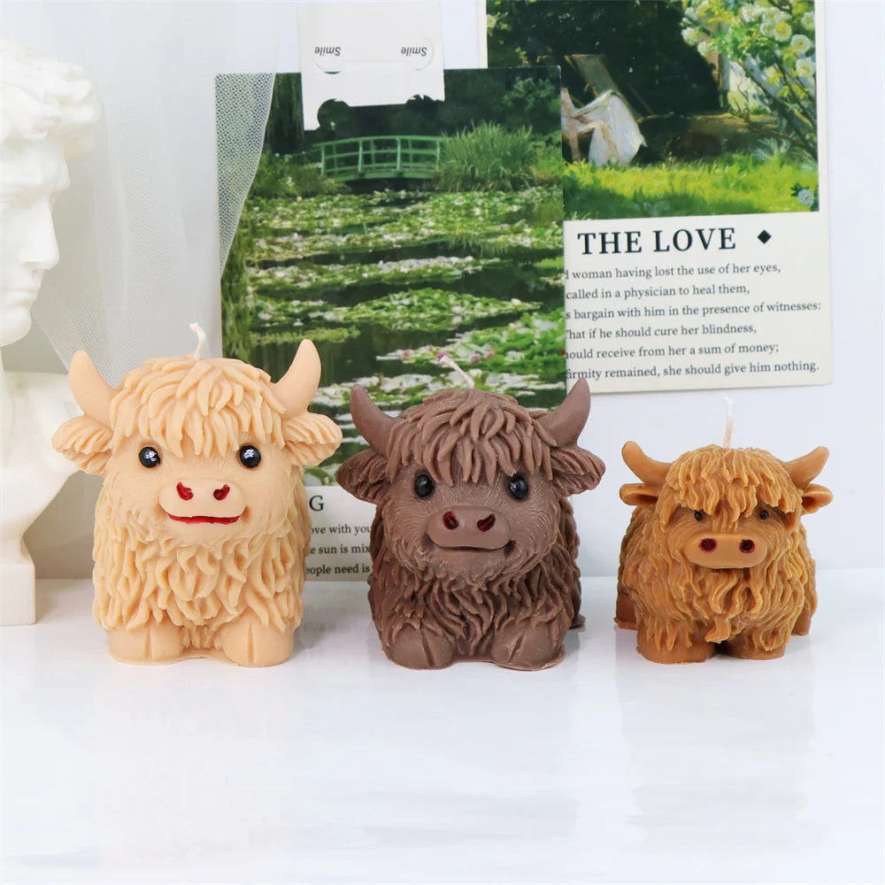 Three silicone molds of Highland cows in various shades of brown and tan used for candles, soap, and crafts.