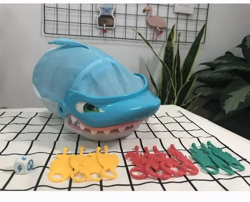A blue shark-shaped toy is displayed with various yellow, red, and green plastic shark teeth accessories on a white surface.