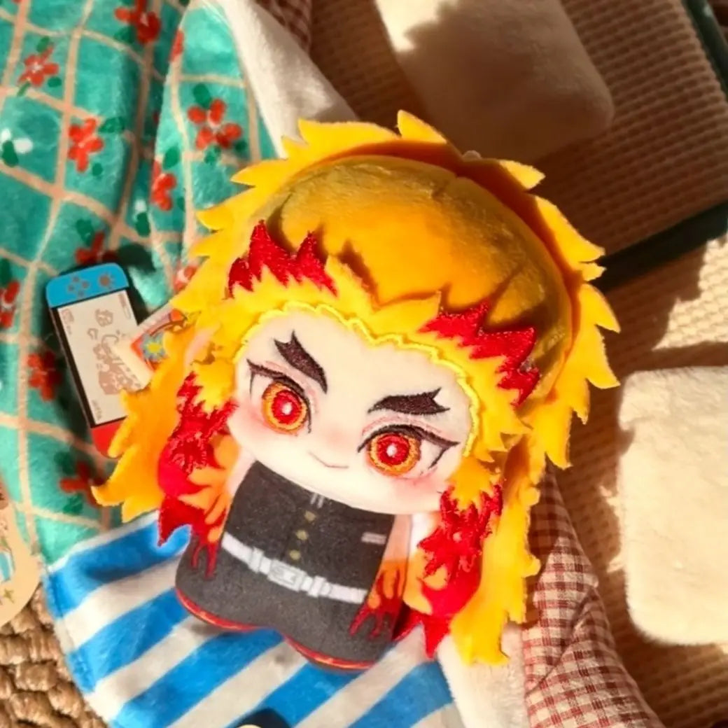 A cute anime plush doll featuring bright yellow hair with red accents and large eyes, displayed on a fabric background.