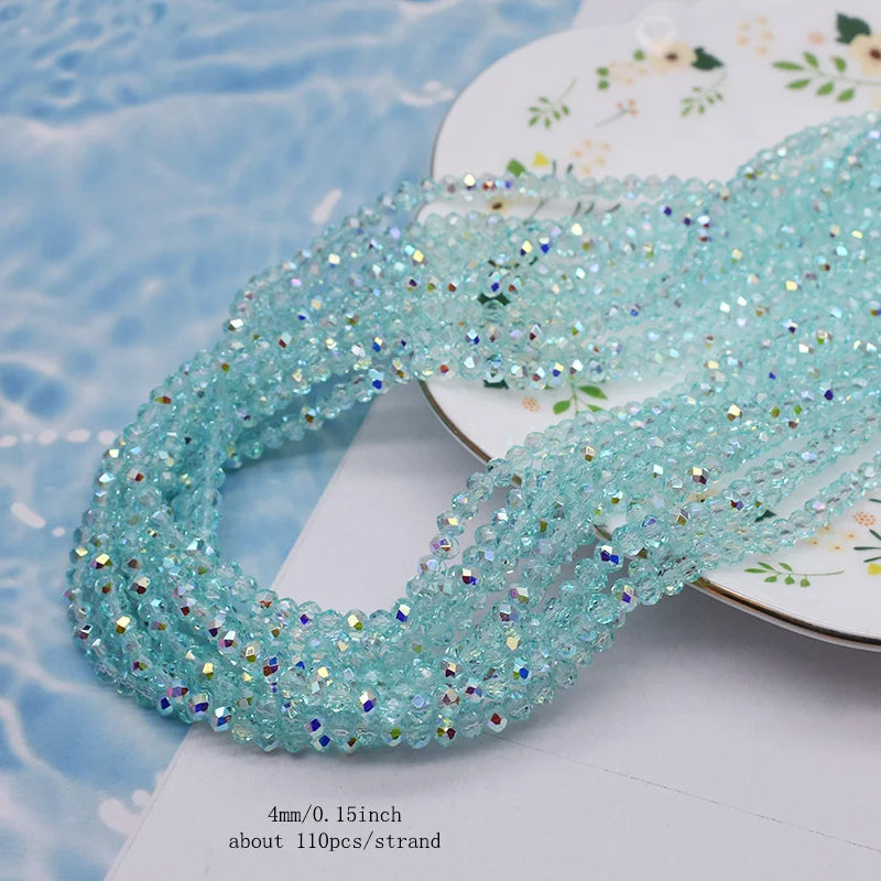 A strand of light blue faceted crystal rondelle beads for jewelry making displayed on a white surface.