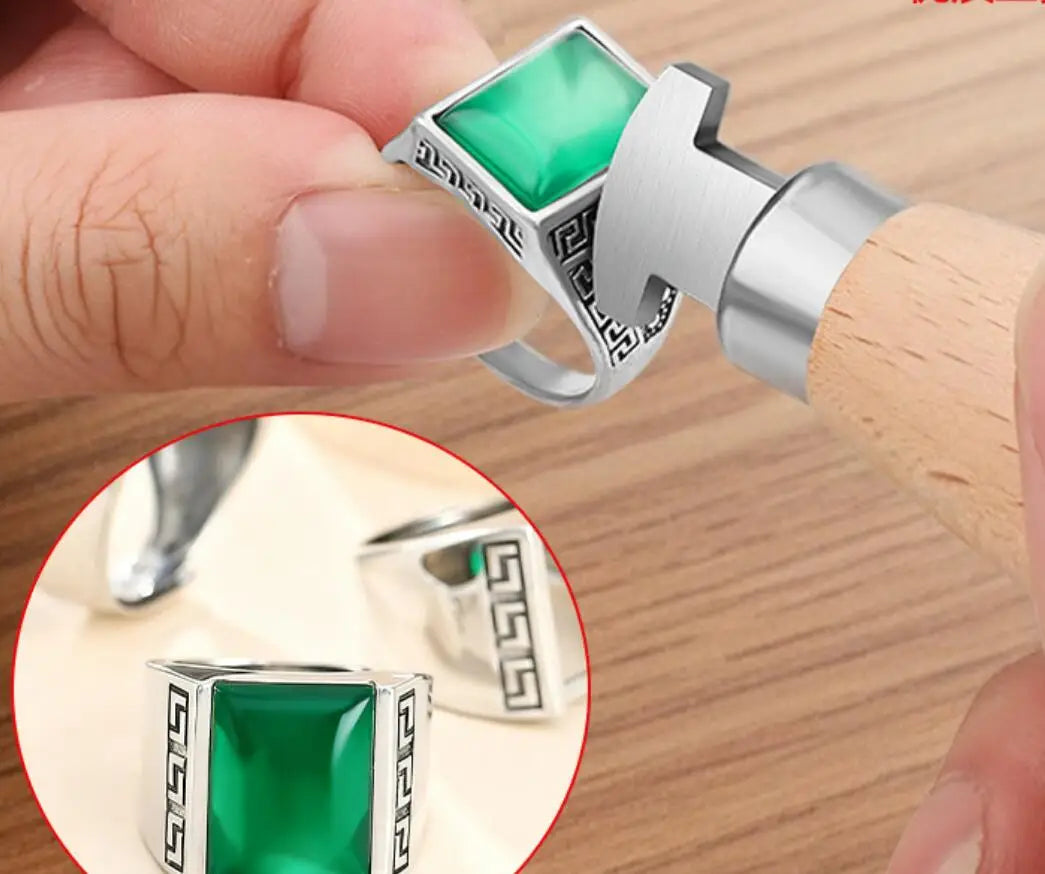 A hand is using a professional bezel setting pusher tool with a silver and green gemstone to set a ring.