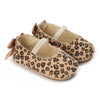 A pair of leopard print soft sole baby sneakers with tan fabric and light beige accents.