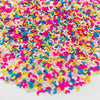 A pile of colorful polymer clay star and heart sprinkles in various shades of pink, purple, yellow, and blue.