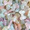 A close-up of iridescent pink and white mermaid bowknot beads for jewelry making.