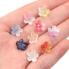 A hand holds a set of 50 glass beads shaped like cherry blossom flowers in various pastel colors.